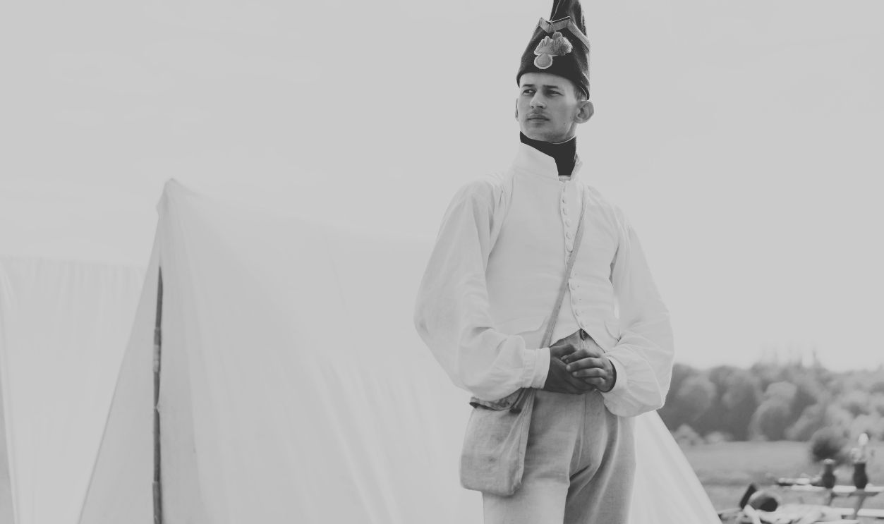 Elegant historical soldier standing beside tents, a classic reenactment scene