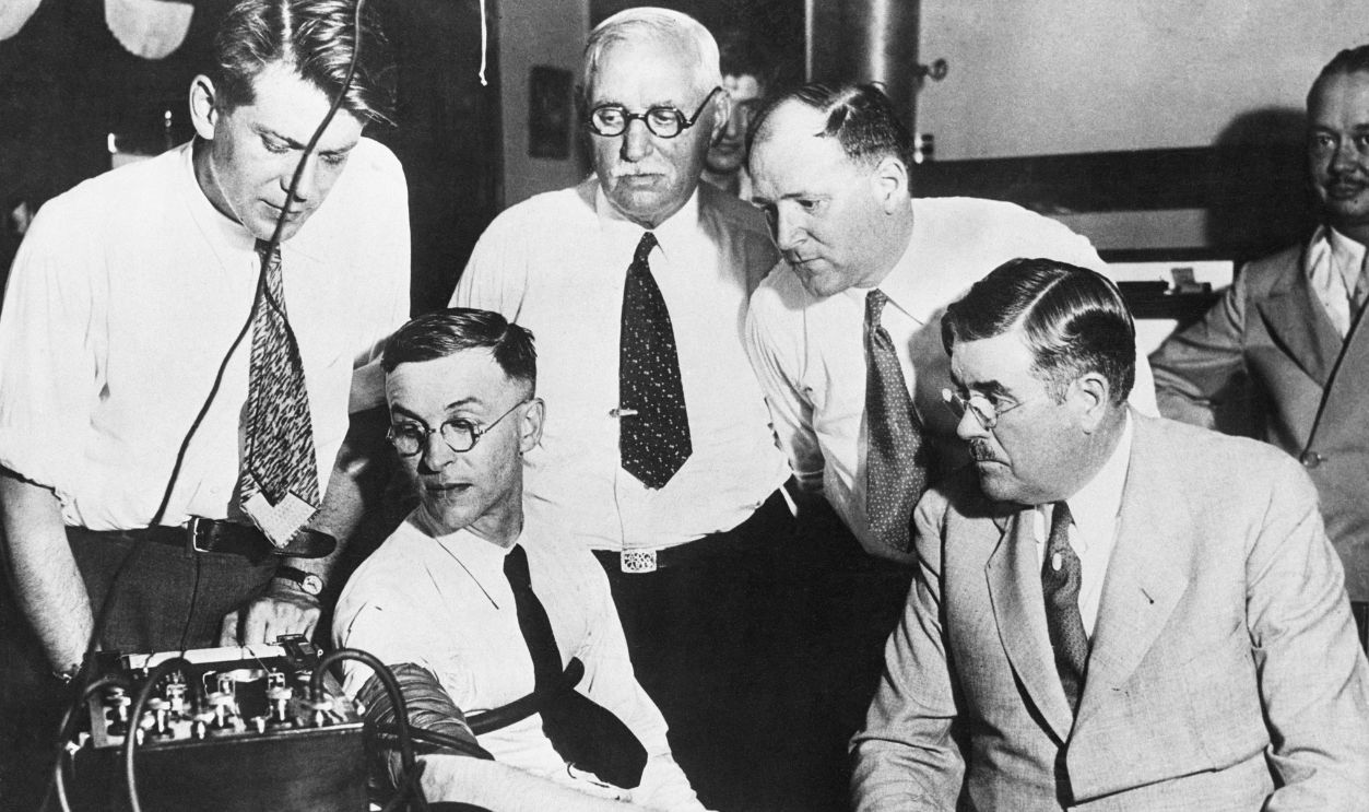 Ivan Grilec being given a lie detector test at the scene of the Carl murder in Chicago. Around him (left to right), Dr. Leonard Keeler of Northwestern University Crime Laboratory; Capt. John Ptacek of the Chicago Police; Charles Vlack, Grilec's attorney and Coroner Frank J. Walsh.
