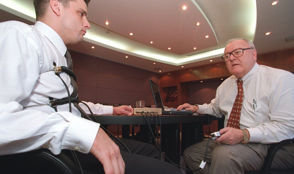 A former Federal Bureau of Investigation (FBI) agent (right) demonstrates a polygraph test on a volunteer, with sensors attached to his fingers and strapped onto his chest. 10 August 2000 