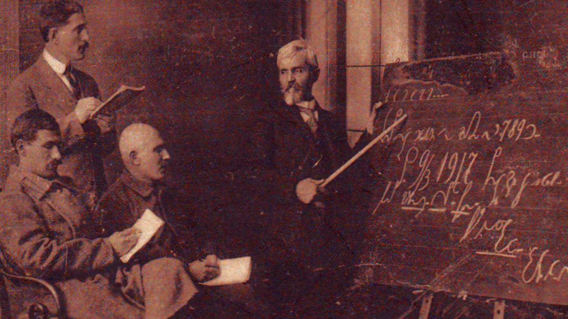Dimiter Jossifov Teaches Shorthand
On the blackboard is written (in Bulgarian stenography): 
Franz Xaver Gabelsberger was born in Munich in 1789. 
Sofia, 9/3 1917, Stenography course for disabled (soldiers). 
Students: Miladinov, Kotsev, Shtilian. 
Teache