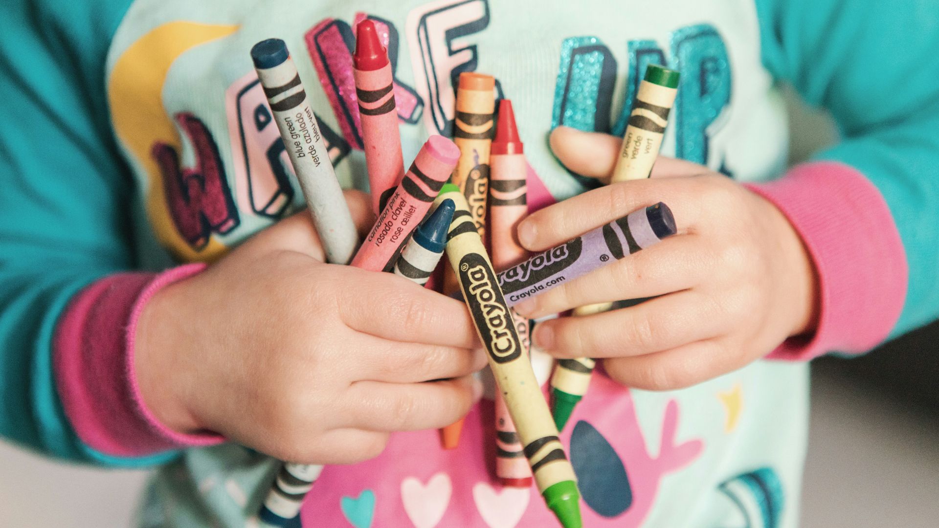 toddler holding assorted-color Crayola lot