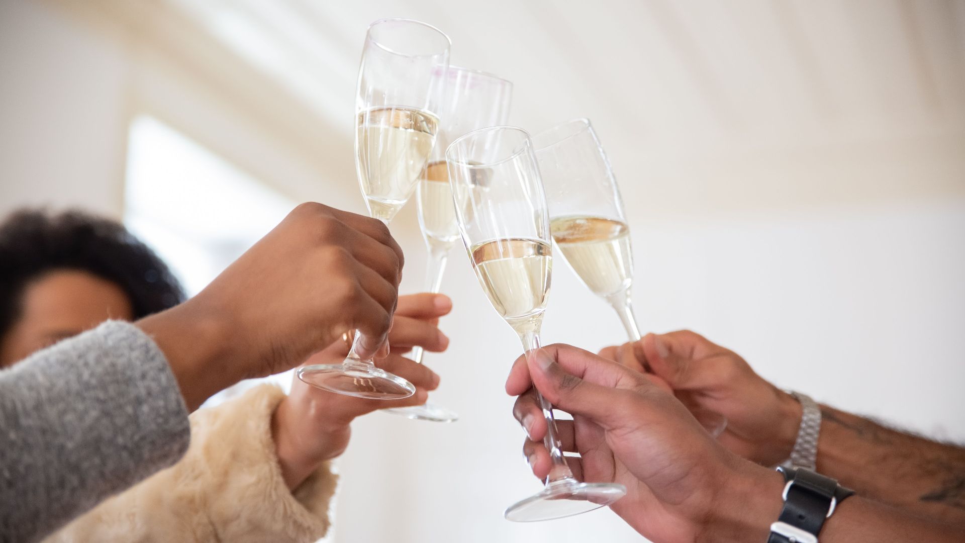 People raising champagne glasses for a celebratory toast indoors. Perfect for party themes.