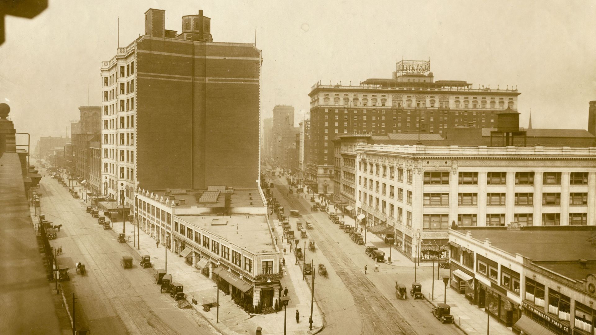Looking down on the junction of Euclid Avenue and Huron Road at East 14th Street. Euclid Avenue is at the right. The north sides of the two streets are shown. Halle Brothers store occupies the large building extending from Euclid through to Huron. The bui