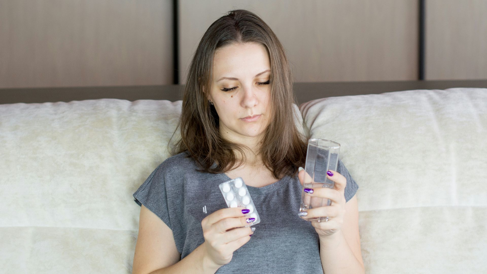 a woman sitting on a couch looking at her cell phone