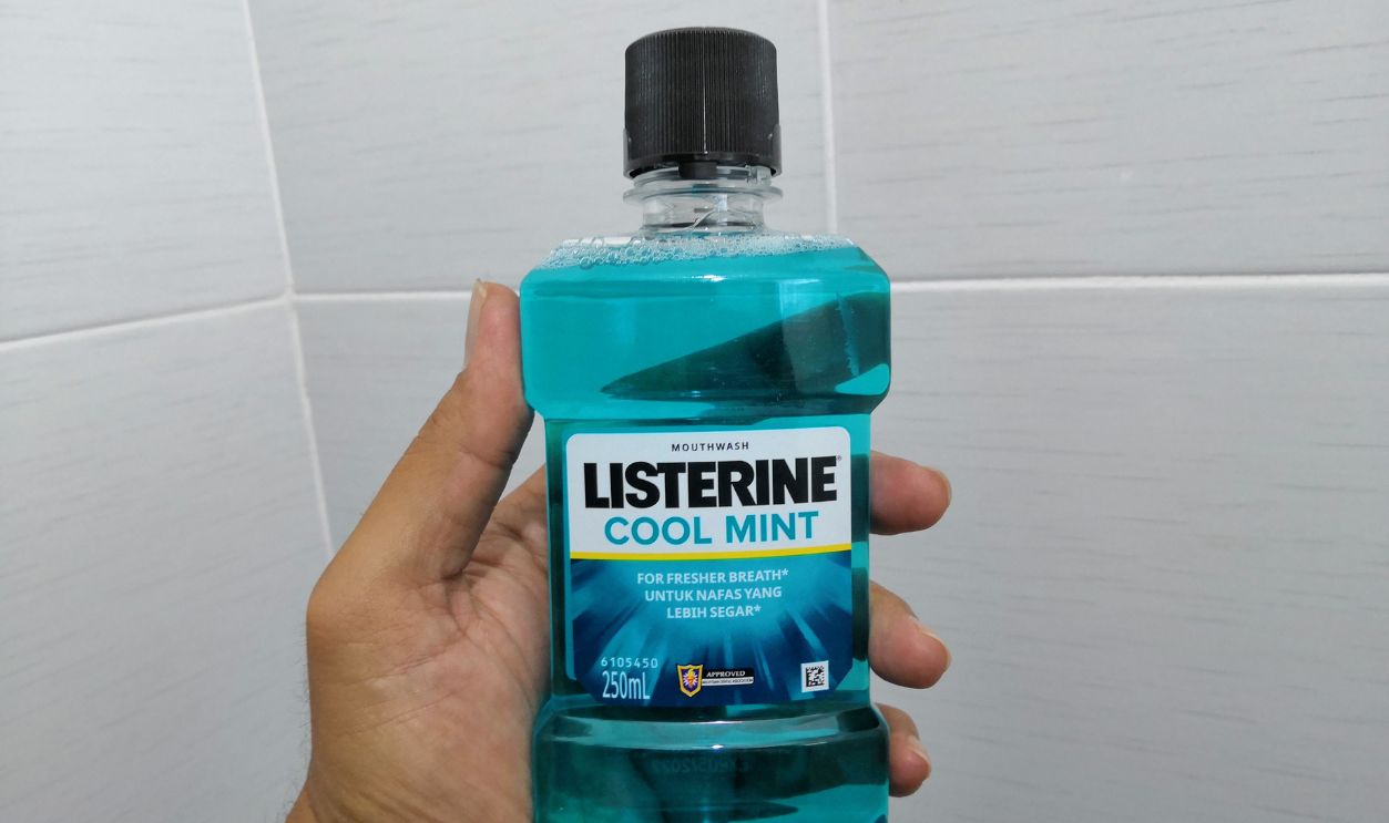 Kuala Lumpur, Malaysia - July 2019 : Hand holding a Listerine mouthwash bottles. Listerine is a brand of antiseptic mouthwash product.