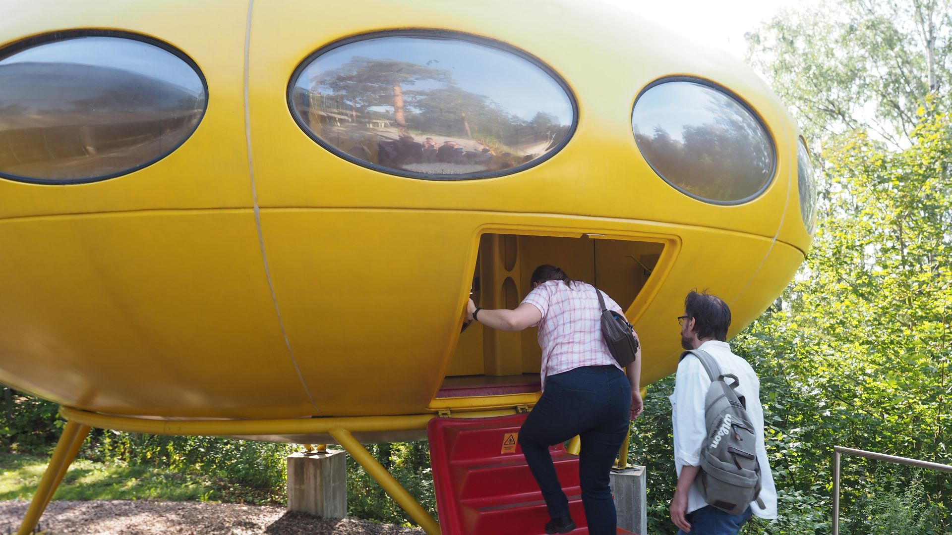 People entering a Futuro house on display at the EMMA museum in Tapiola, Espoo, Finland. Entry to a Futuro house is via a set of fold-out stairs. Photographed during Espoo Day 2019.