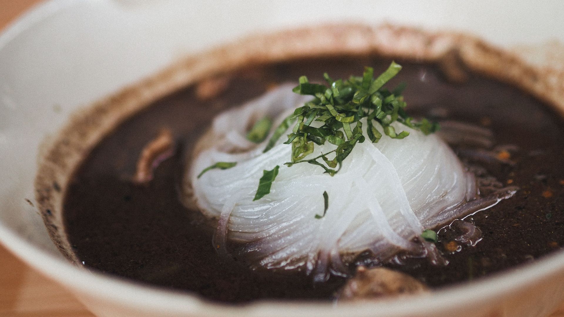 Close-up of a delicious Asian noodle soup garnished with fresh herbs.
