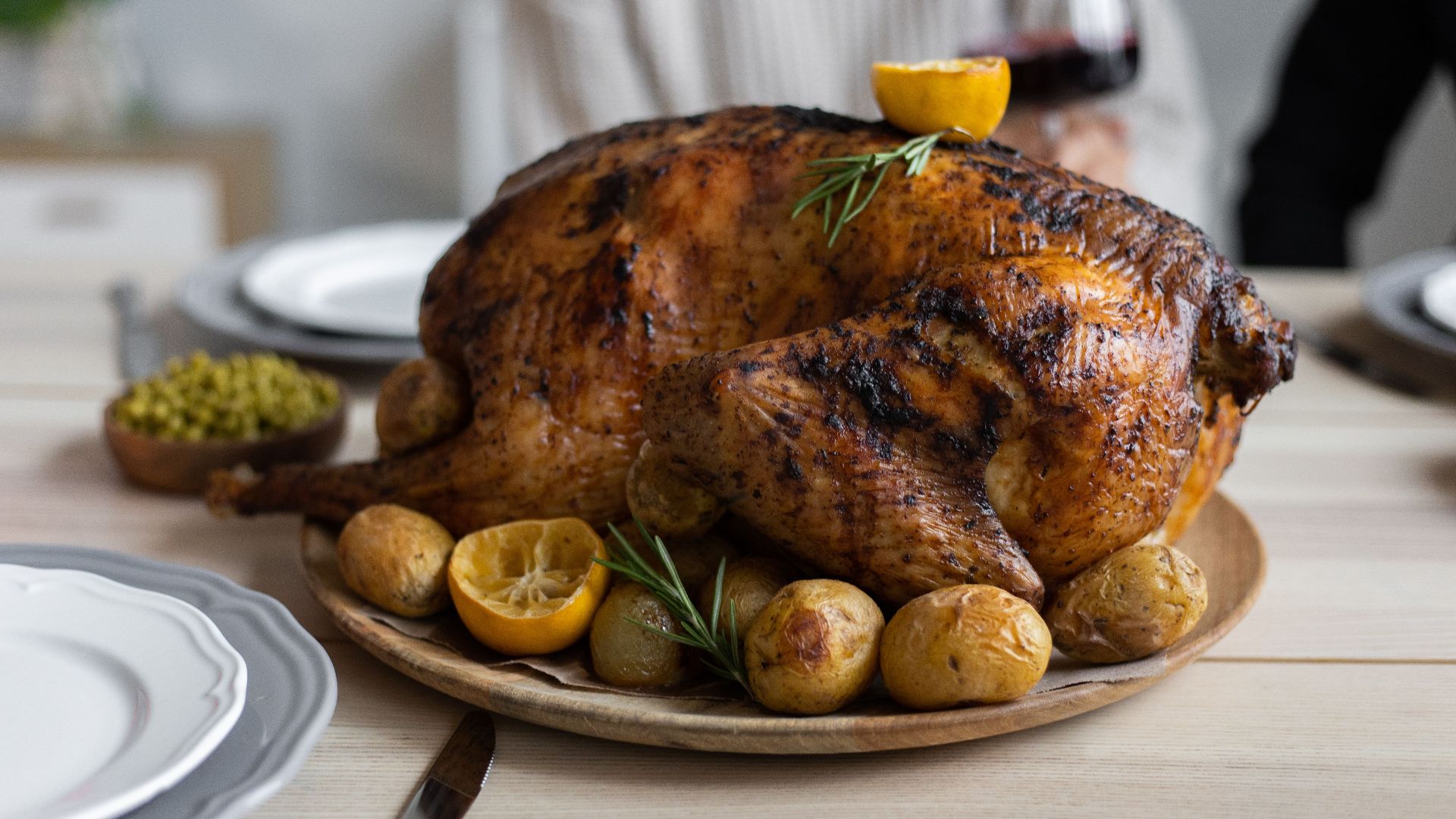 From above of big turkey roasted with lemon and potatoes on round wooden tray placed on table for celebrating Thanksgiving Day