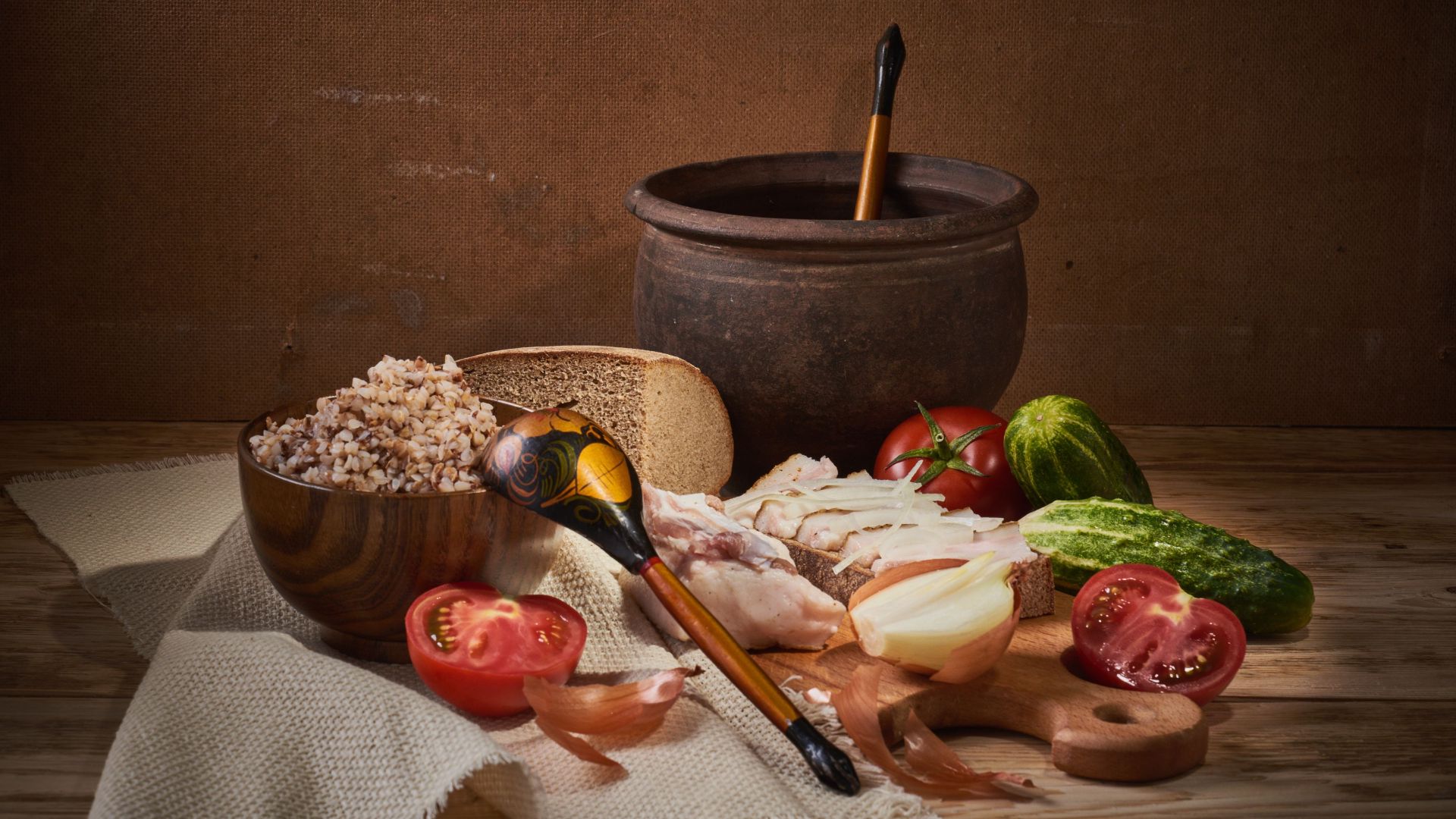 Cozy rustic still life featuring buckwheat, vegetables, and traditional tableware on a wooden surface.