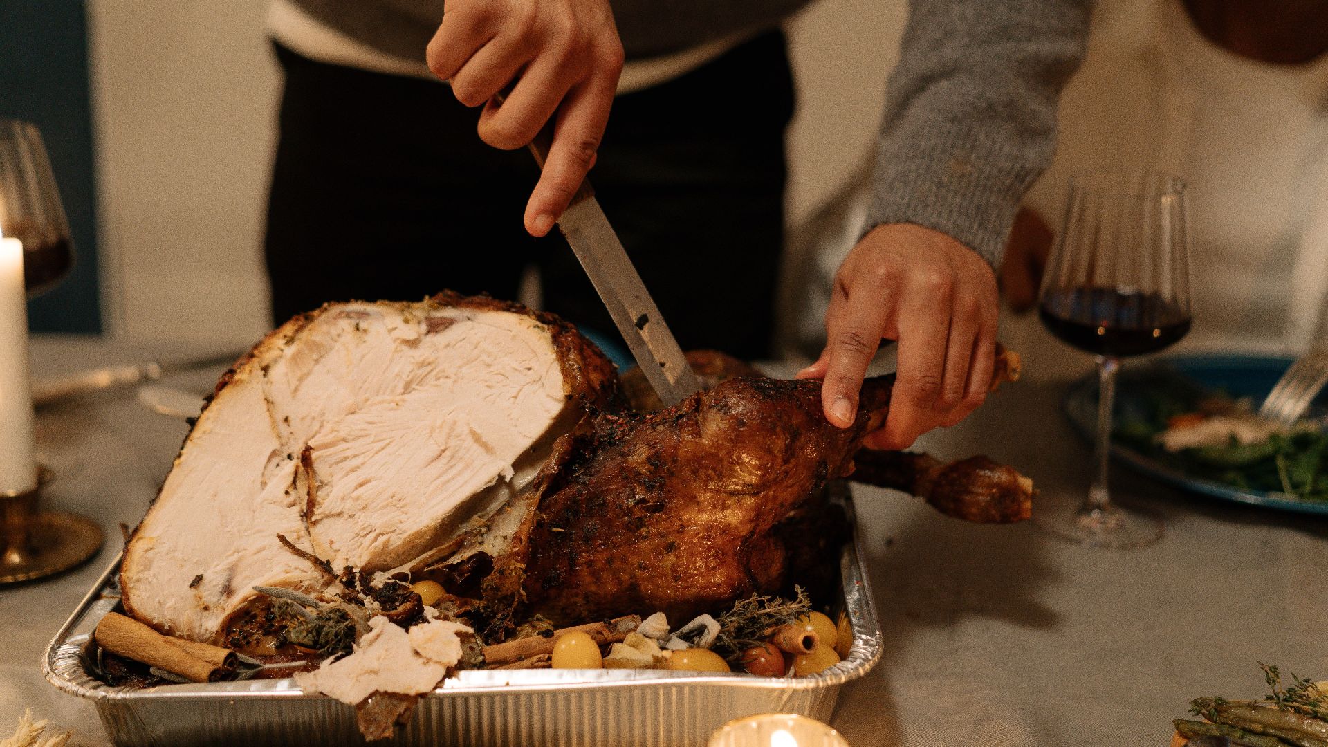 Person carving a delicious roasted turkey during a festive holiday dinner setting.