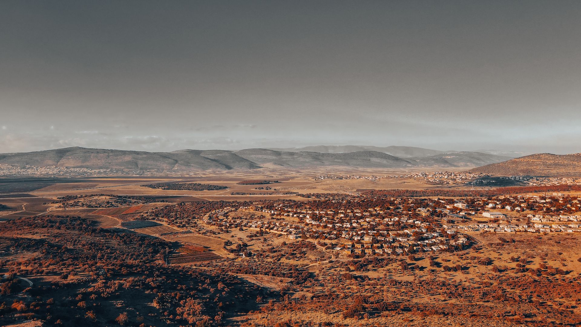 Aerial shot of North District, Israel, showcasing hills and residential areas under a warm sky.