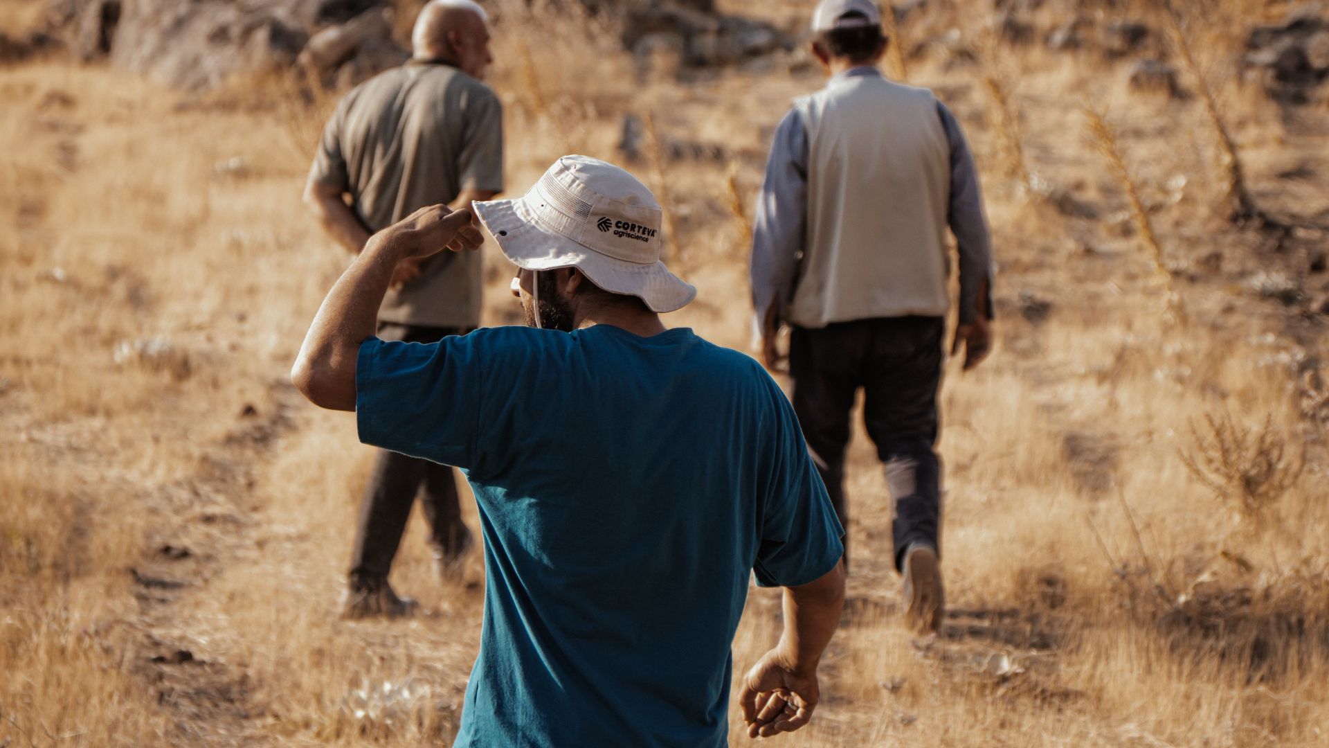 A group of people hiking through a dry, rocky landscape under a sunny sky, showcasing adventure and exploration.