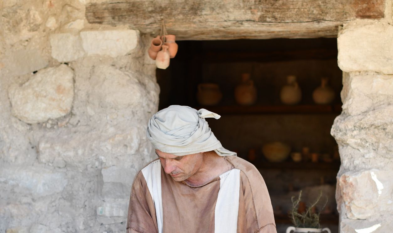 Potter wearing headscarf works with clay in a traditional rustic workshop