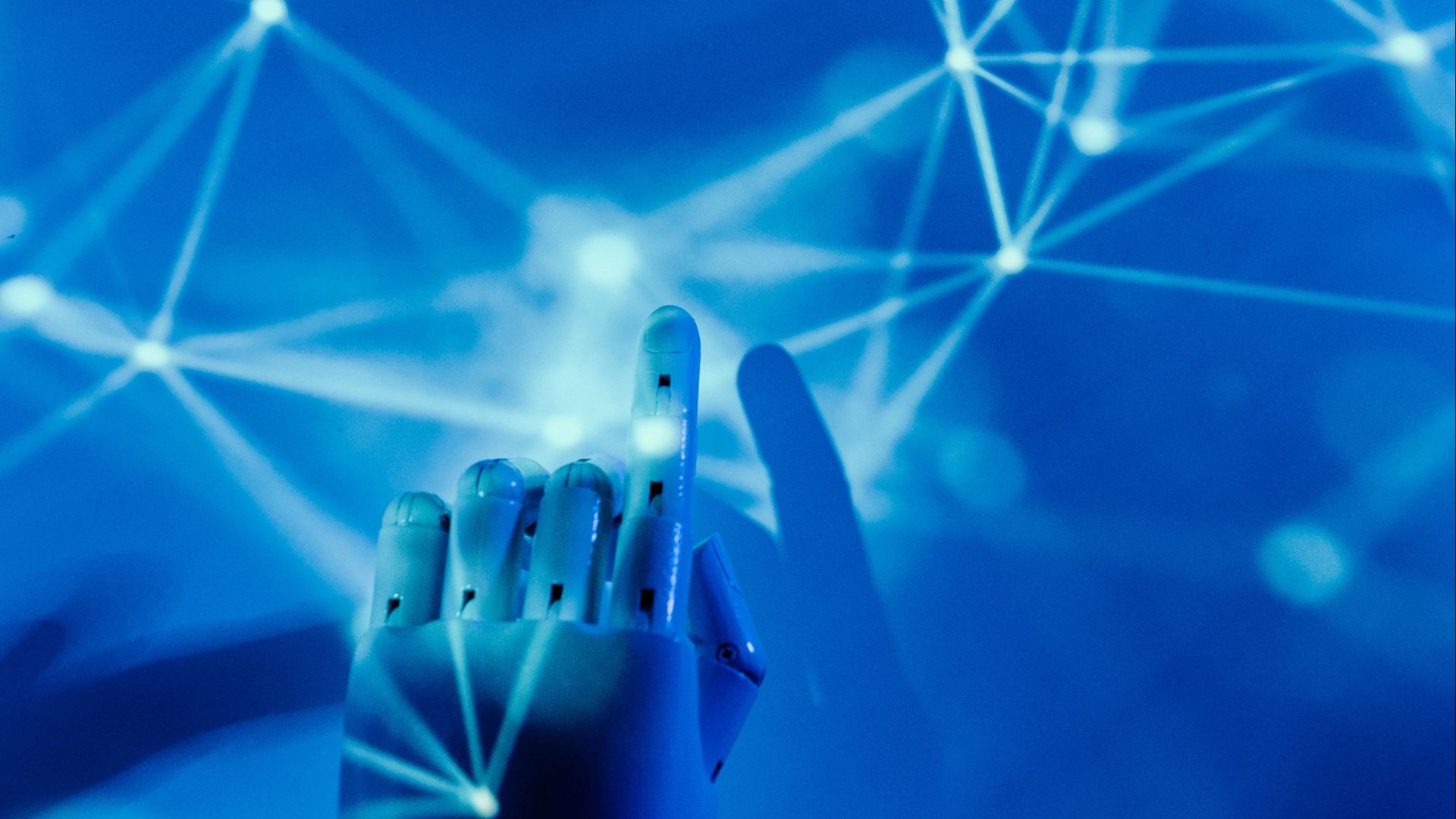 Futuristic robotic hand touching a digital network on a blue background.