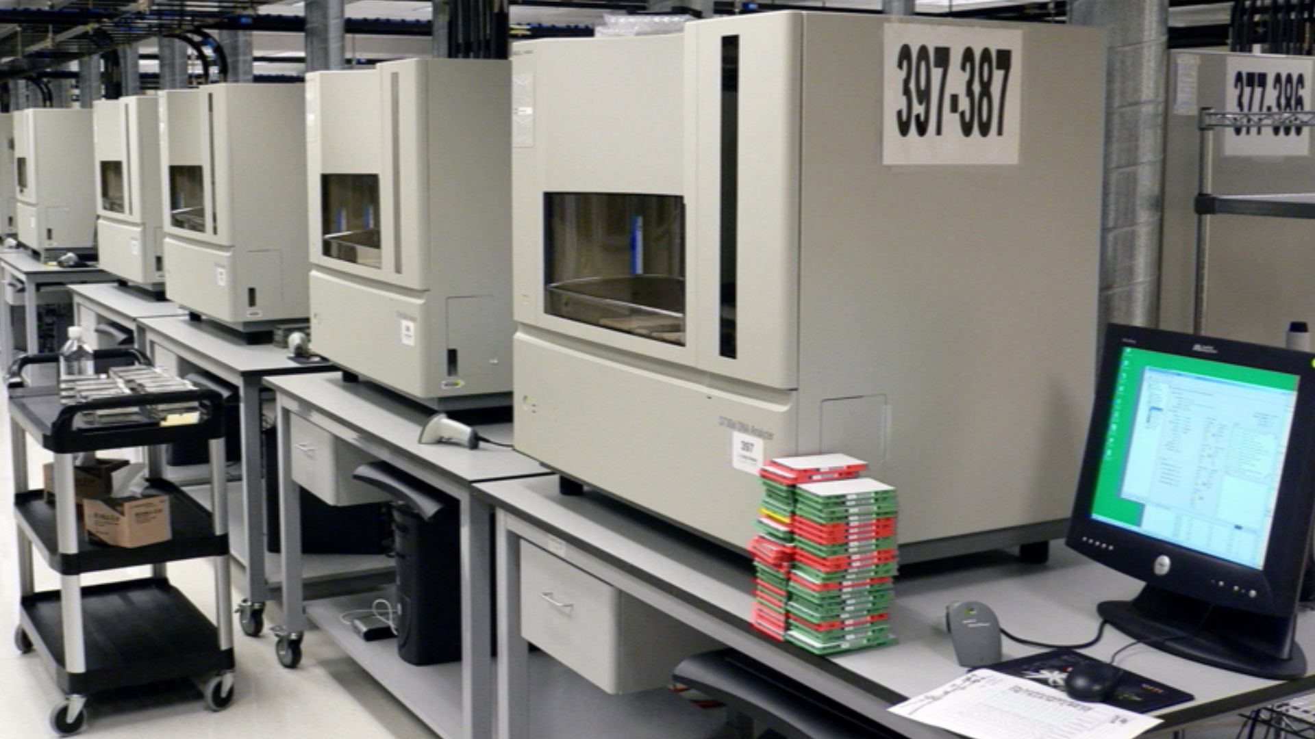A row of DNA sequencing machines on SteelSentry tables (3730xl DNA Analyzer machines from Applied Biosystems).