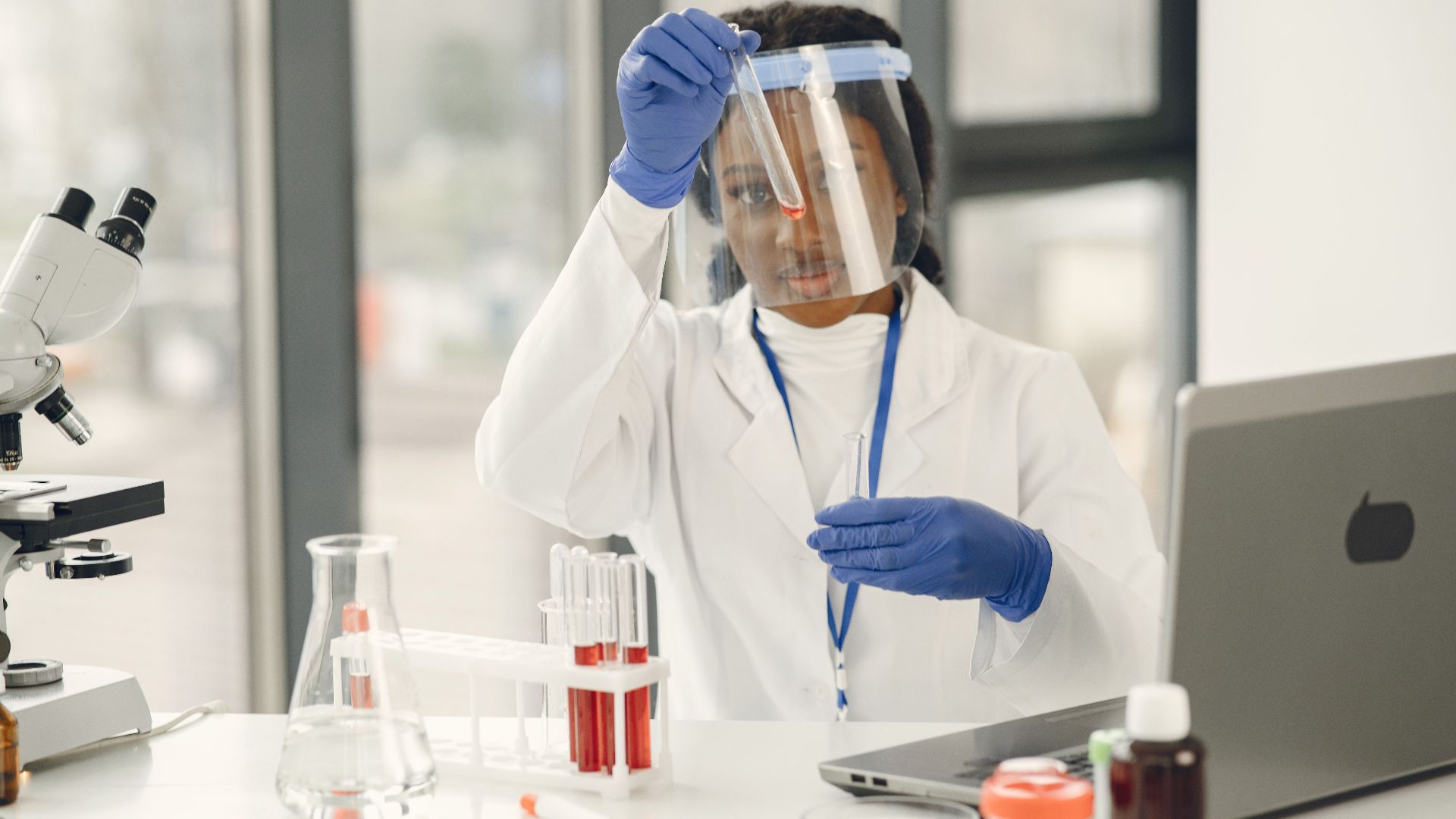 Female scientist working with test tubes and microscope in a laboratory.
