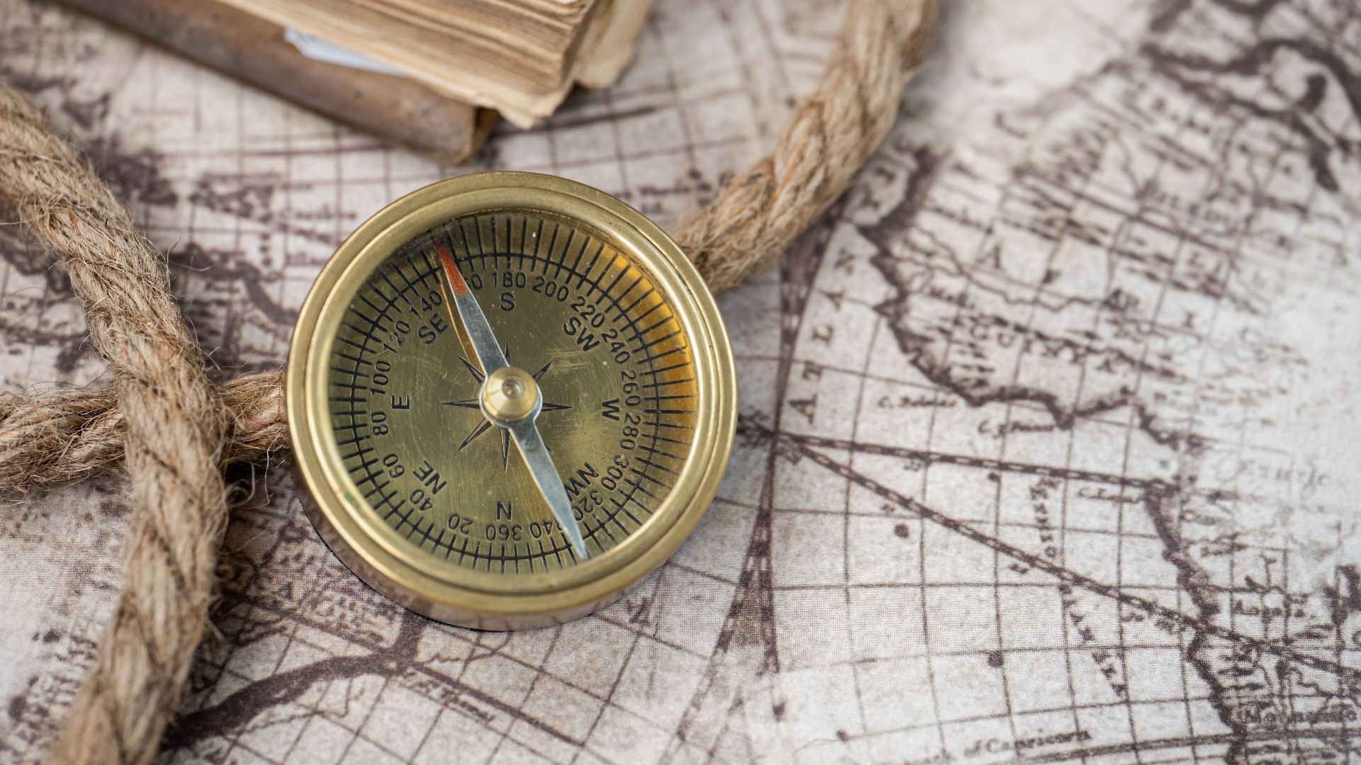 A close-up of a vintage compass on an antique world map, depicting navigation history.