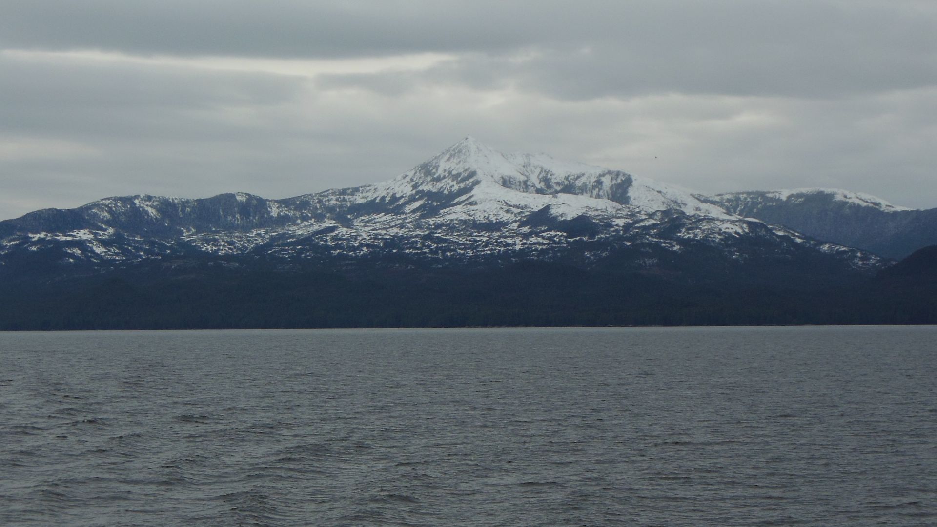 A snowy peak (Mount Buxton) on Calvert Island on the coast of British Columbia, Canada, seen from a passing ferry boat