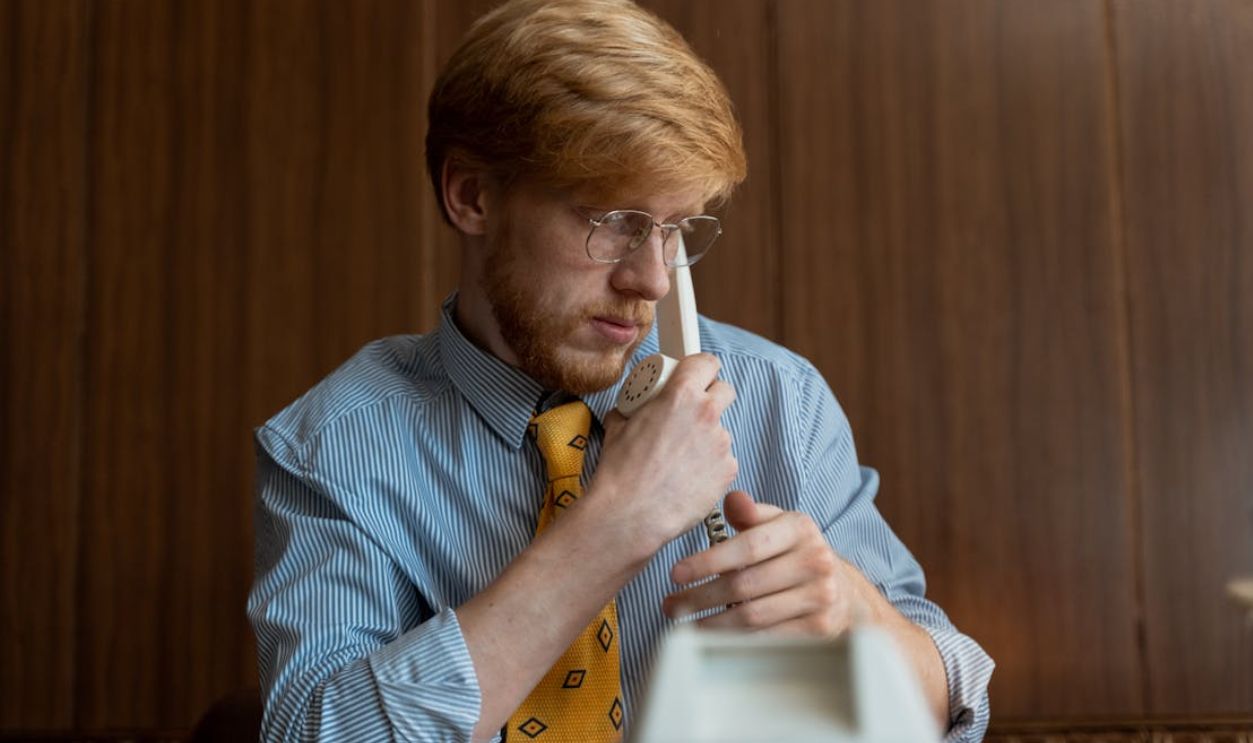 Young businessman wearing a striped shirt and glasses engaged in a phone call inside an office