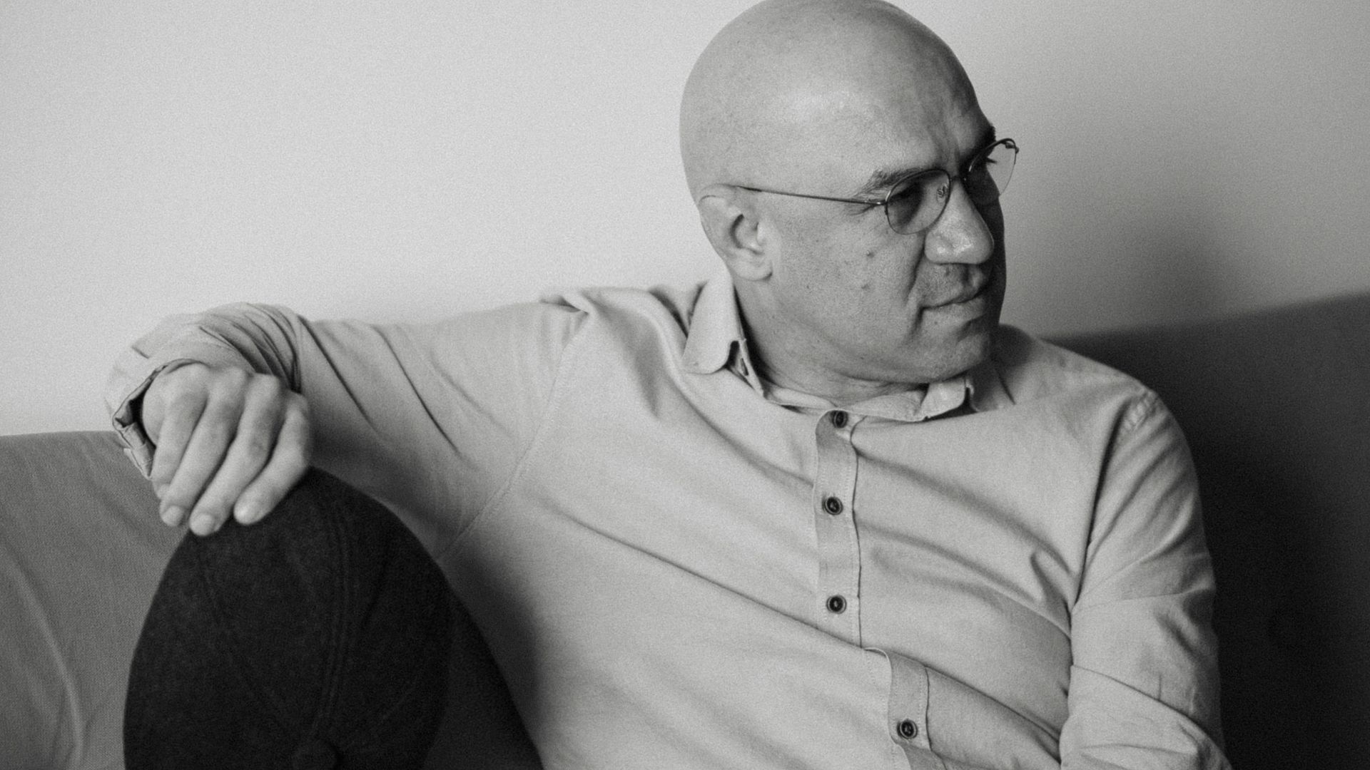 A black and white photo of a man sitting on a couch