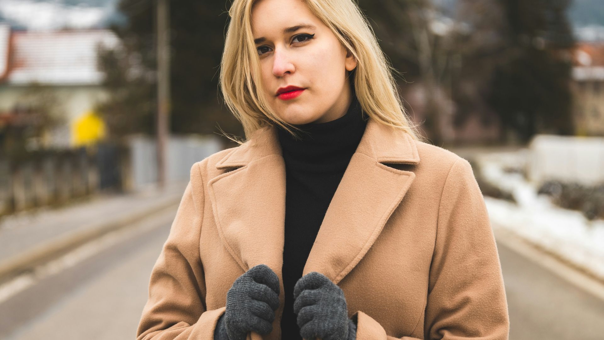 a woman standing on a road wearing a coat