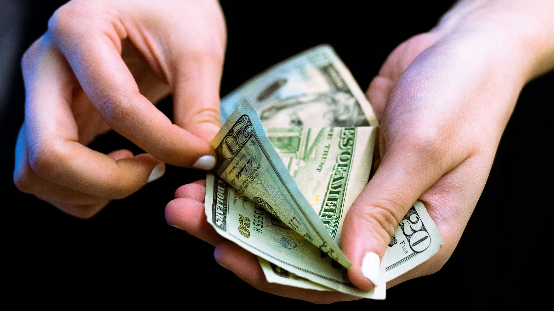 person holding fan of 100 us dollar bill