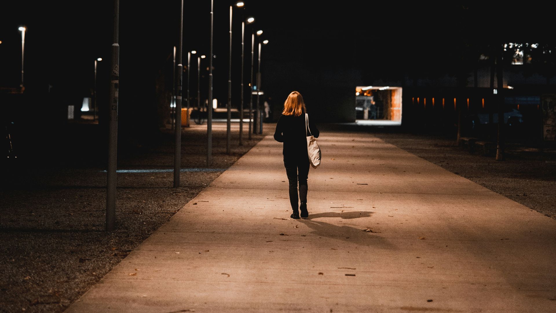 a woman walking down a sidewalk at night