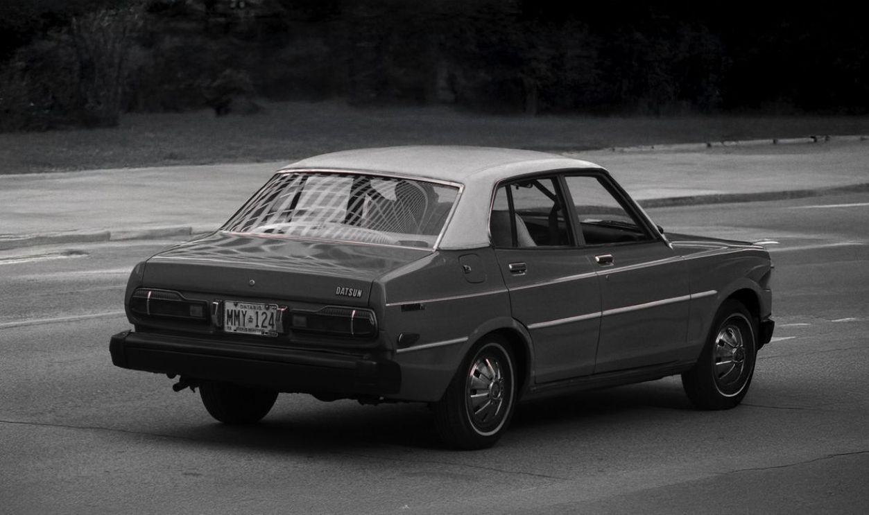 Vintage Datsun in black and white cruising down the streets, capturing nostalgic automotive design