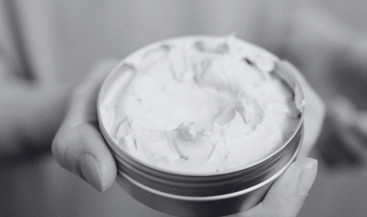 Close-up of hands holding a tin of cream, ideal for skincare routines and healthcare themes