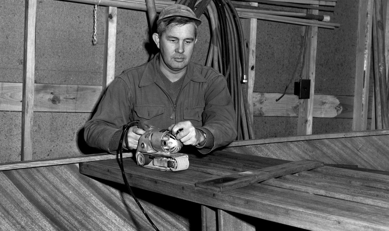Boat Builder Sanding Wood In Nashville A view of a man sanding the boat seat of a boat that he's building in 1953 in Nashville, Tennessee.