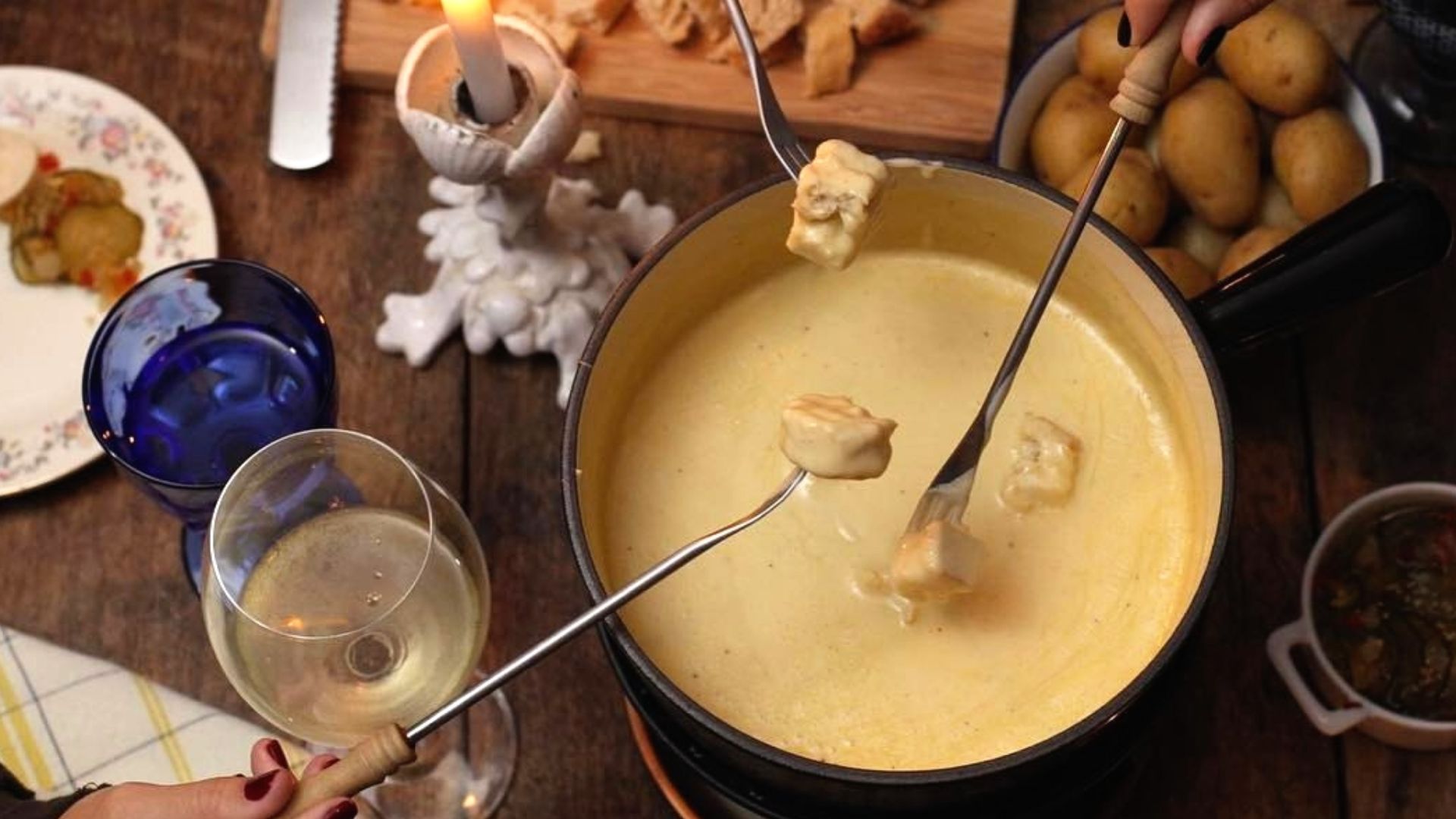 Fondue served with bread, potatoes, and white wine