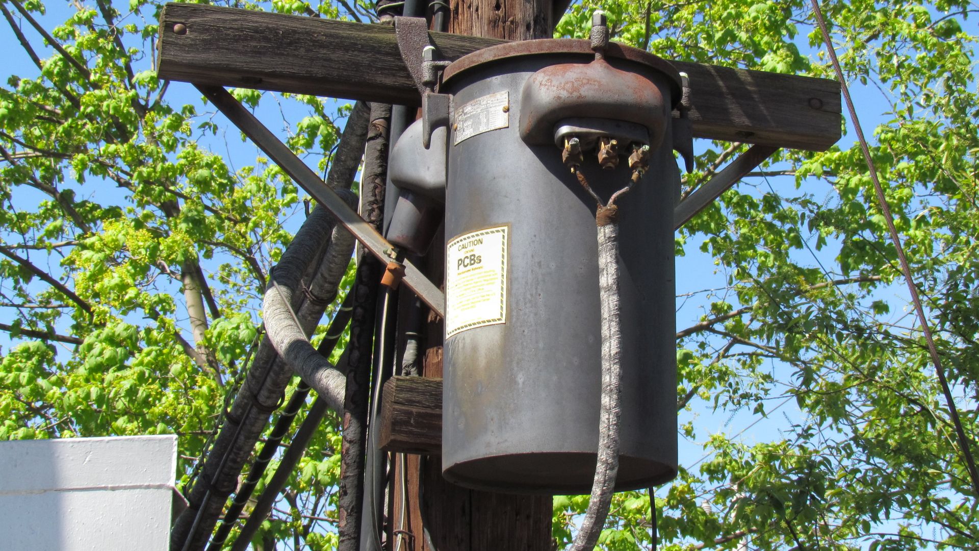 Railroad signal power supply transformer dating from the 1930's at CP-SLOPE interlocking, west of Altoona with a warning label indicating that it contains PCBs.