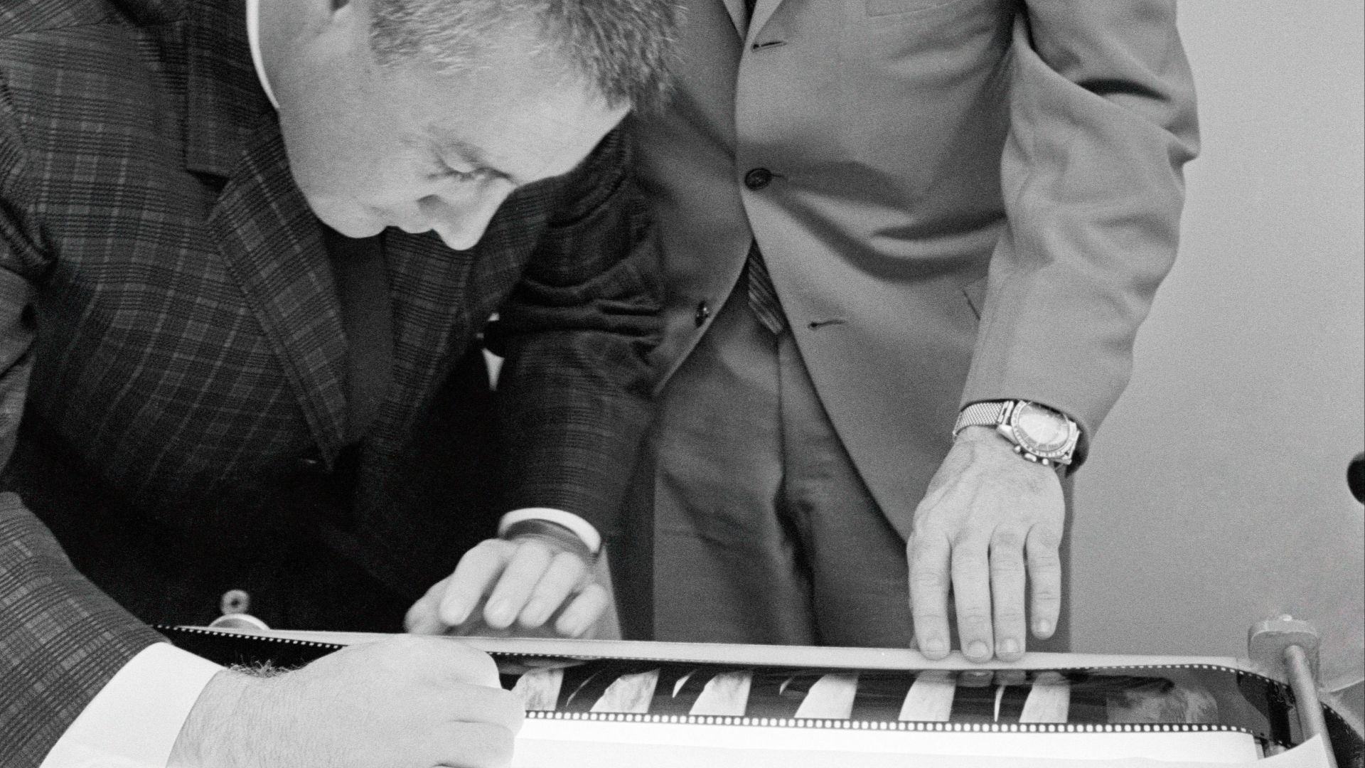 Gemini-Titan 3 astronauts Virgil I. Grissom (left) and John W. Young examine some of the negatives of photographs taken on their three-orbit flight on March 23, 1965.