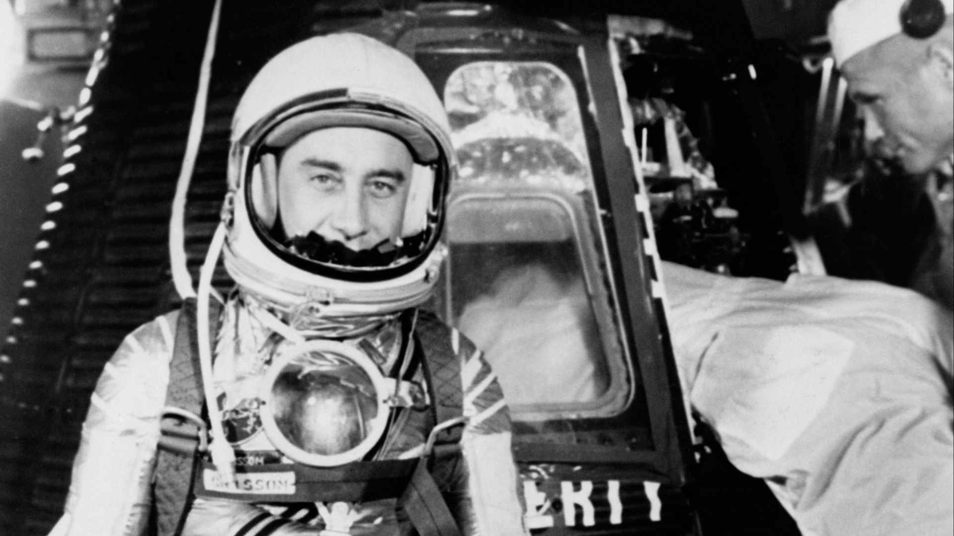 S61-02888 (1961) --- Astronaut Virgil I. (Gus) Grissom, suited up and ready to climb into Liberty Bell 7 spacecraft, stands in front of the capsule for a picture. Backup pilot John Glenn is in the right corner of the view behind Grissom. The Mercury-Redst