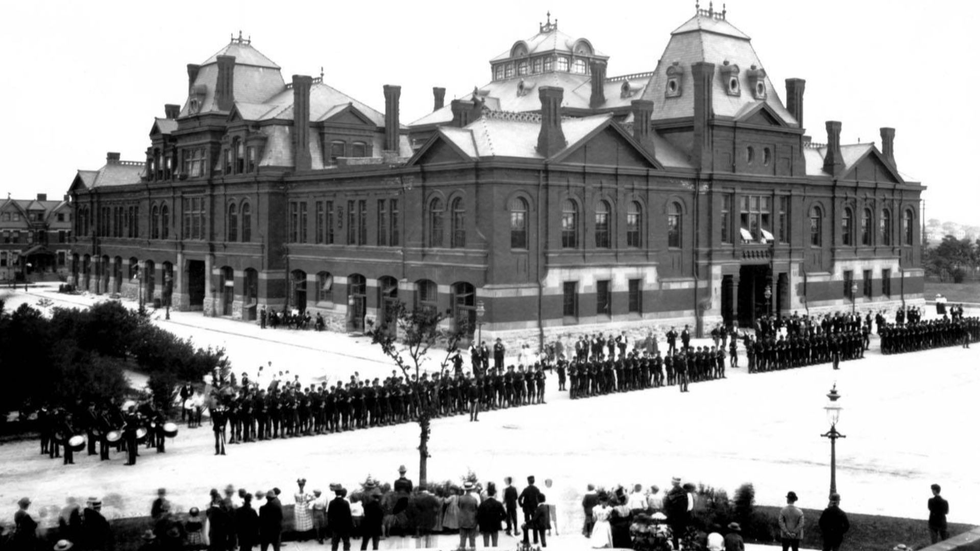 Pullman strikers outside Arcade Building in Pullman, Chicago. The Illinois National Guard can be seen guarding the building during the Pullman Railroad Strike in 1894. Photographed from the Florence Hotel by the Pullman Company staff