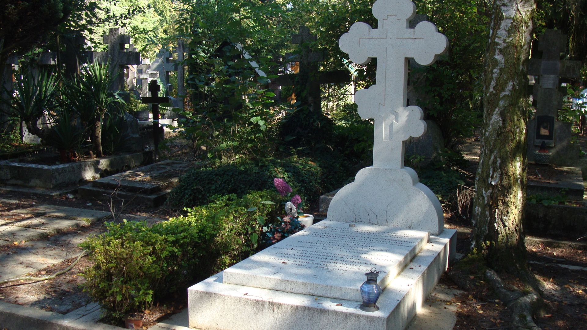 The grave of Polish ballet dancer Matylda Krzesińska and her husband and son in white stone at the Sainte-Geneviève-des-Bois Russian Cemetery with the writing on the tombstone visible and in the lower partly readable.