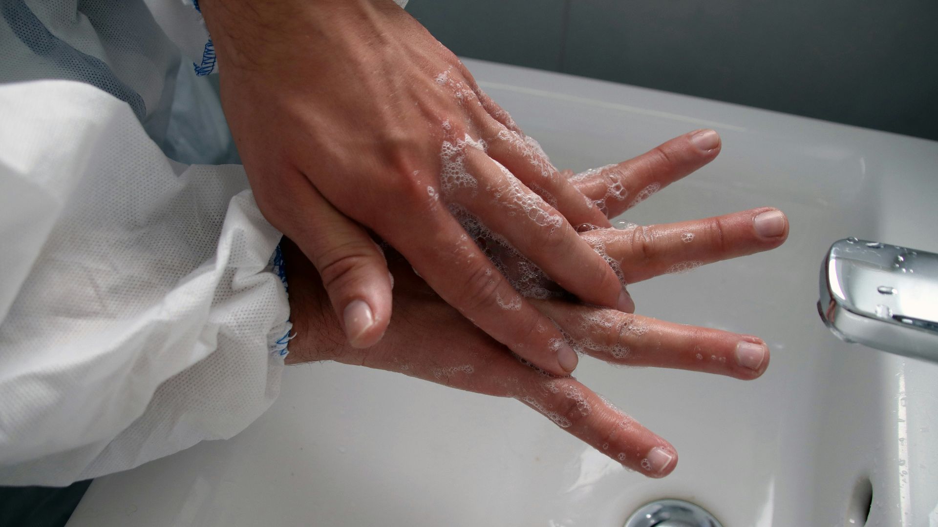 persons hand on white ceramic sink