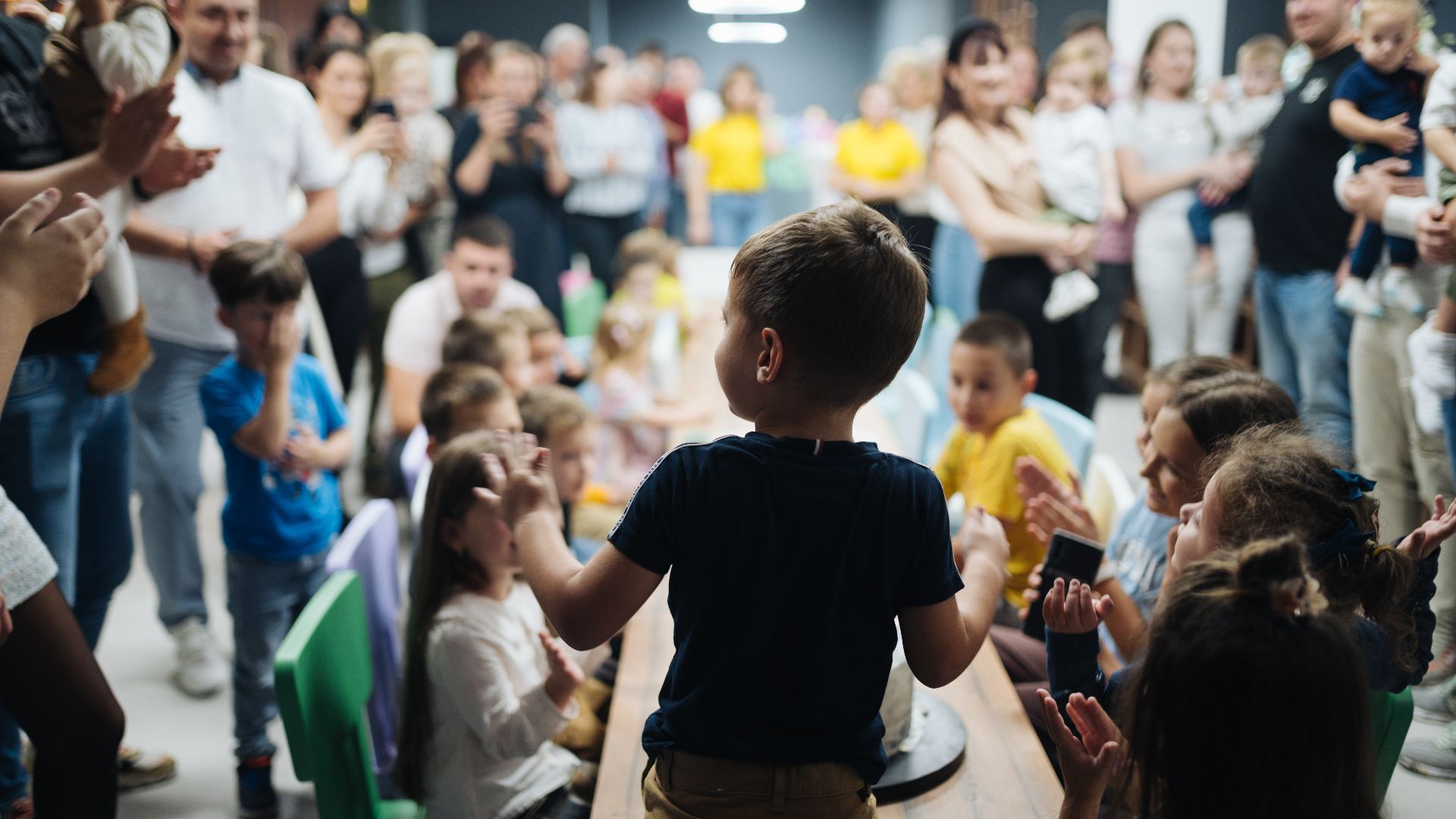 Back view of a kid blowing candles at birthday party