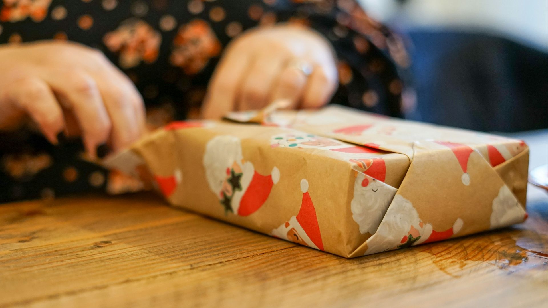 a person wrapping a present on a wooden table