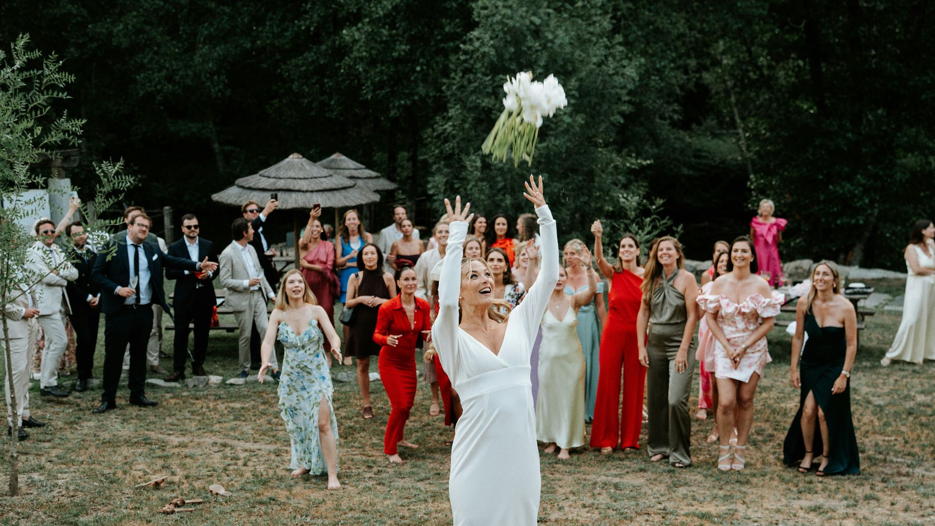 Bride throws bouquet to wedding guests outdoors