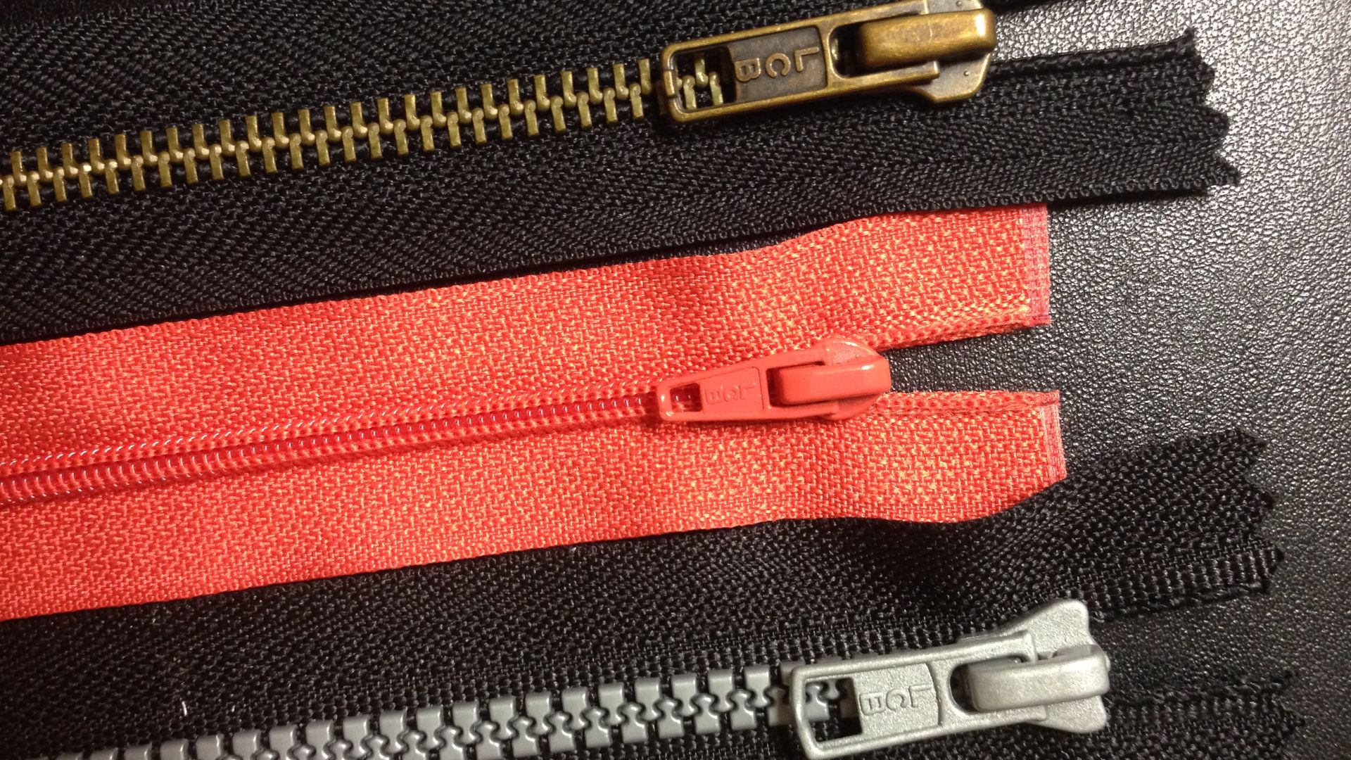 Zippers with coil, plastic or metal teeth. The initials on the pull tab (puller) usually stand for the zipper's brand name.