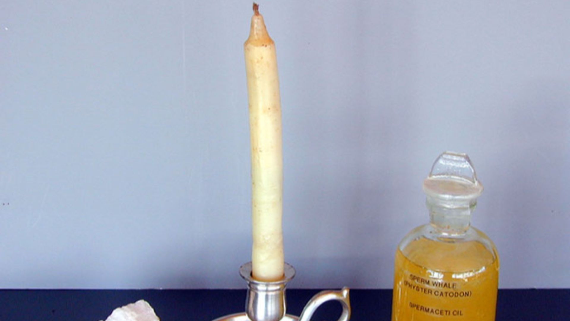 A sample of spermaceti wax, a spermaceti candle, and a jar of sperm oil.