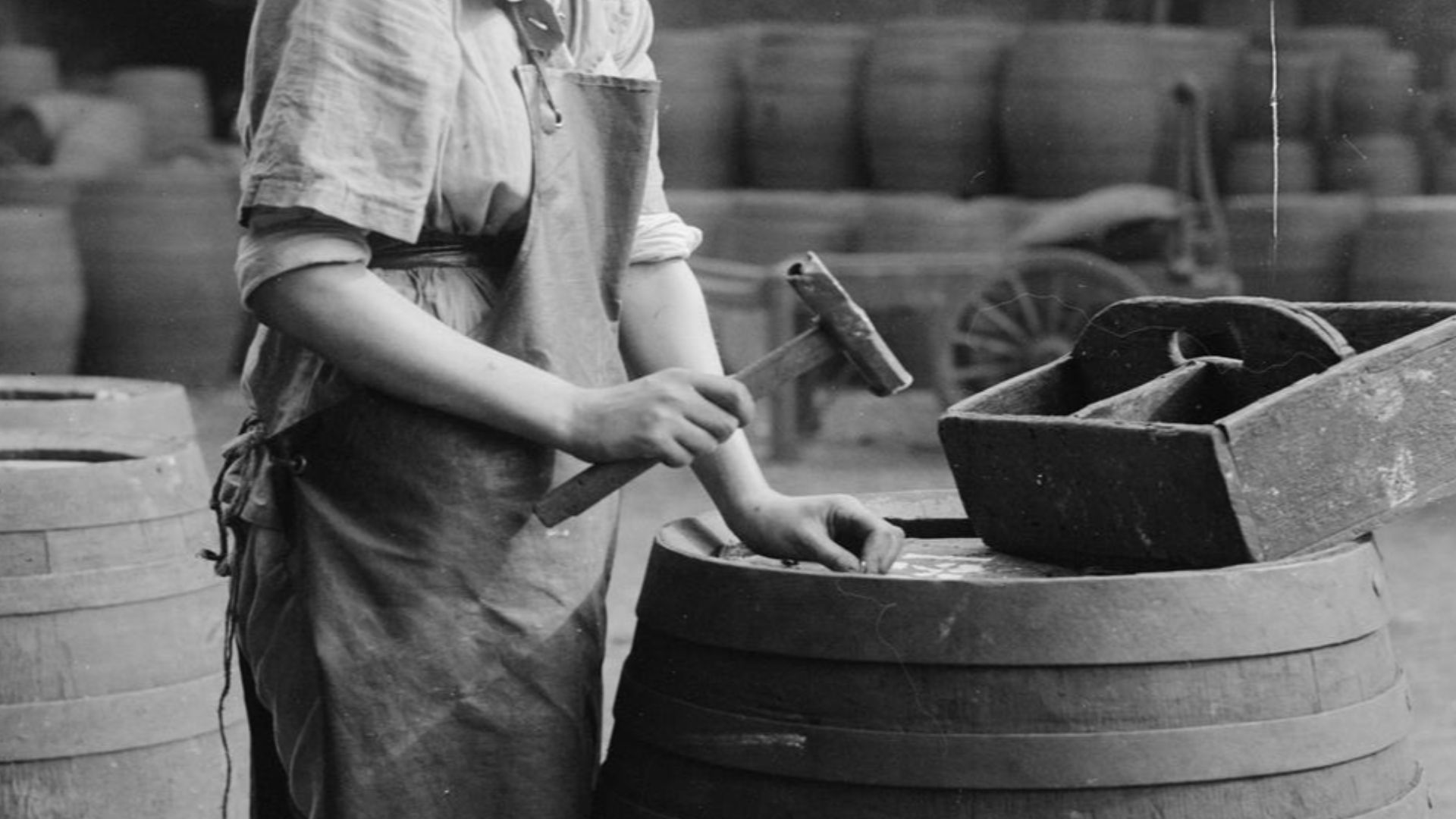 The Employment of Women in Britain, 1914-1918
A portrait of a female brewer, as she use a hammer and nails to secure the lid of a cask or barrel at a brewery in London.