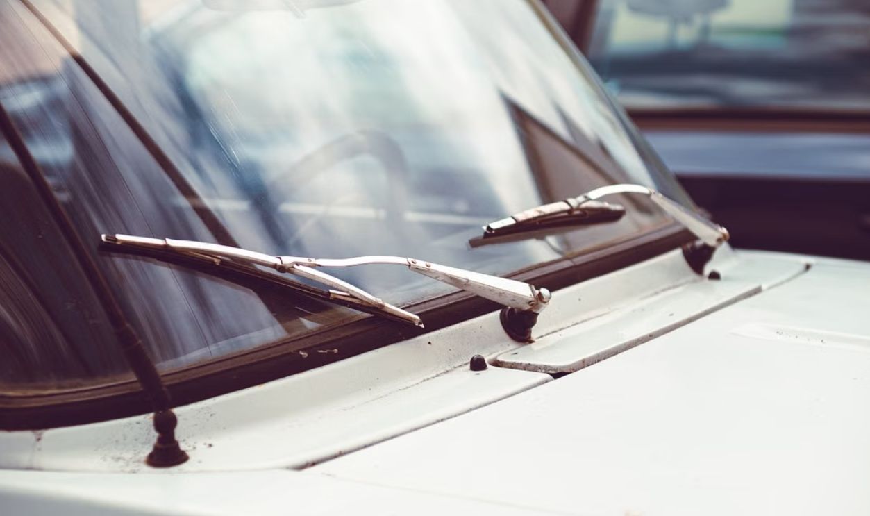 Detailed image of an old car windshield with rusty wipers and vintage appeal