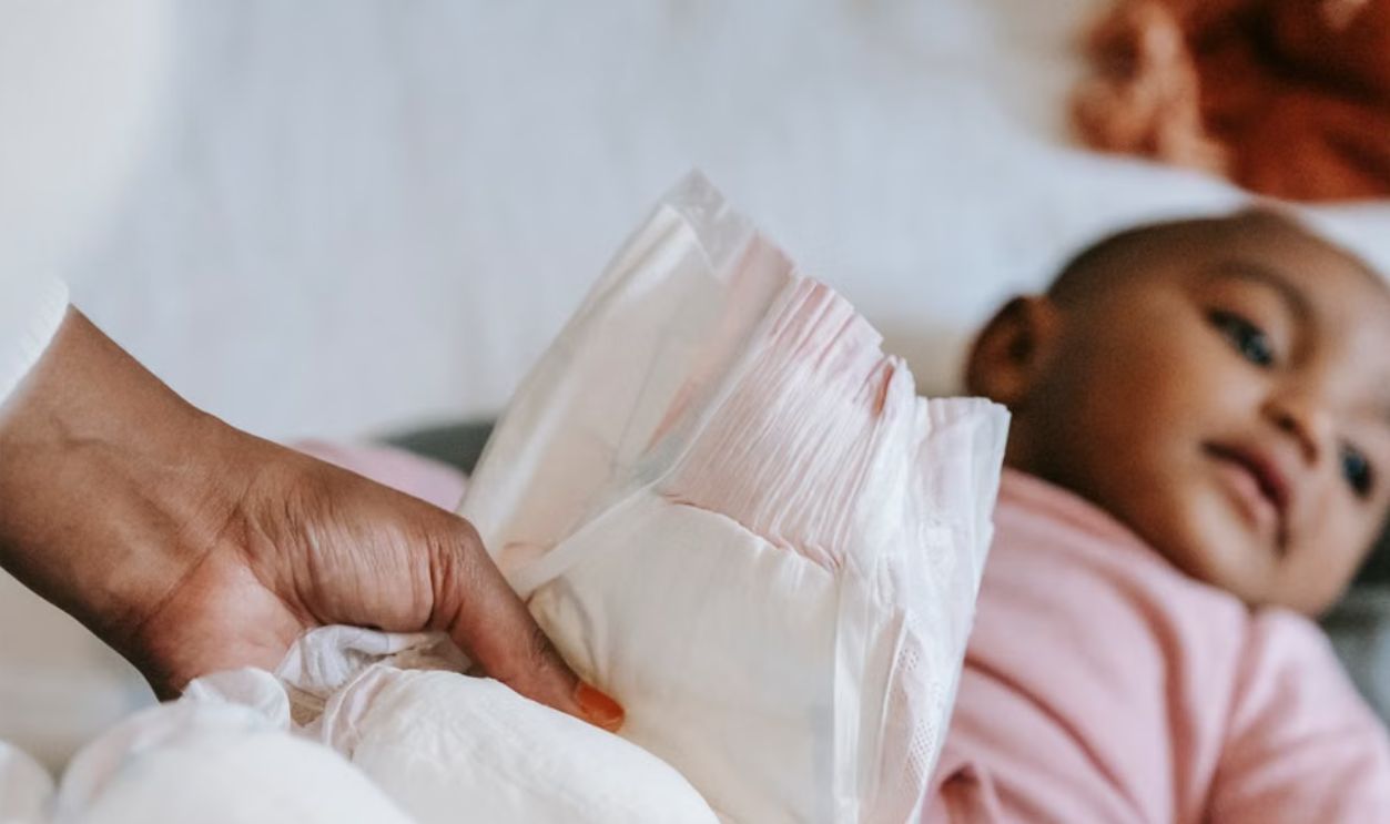 A mother gently changes her baby's diaper in a calm, cozy home setting