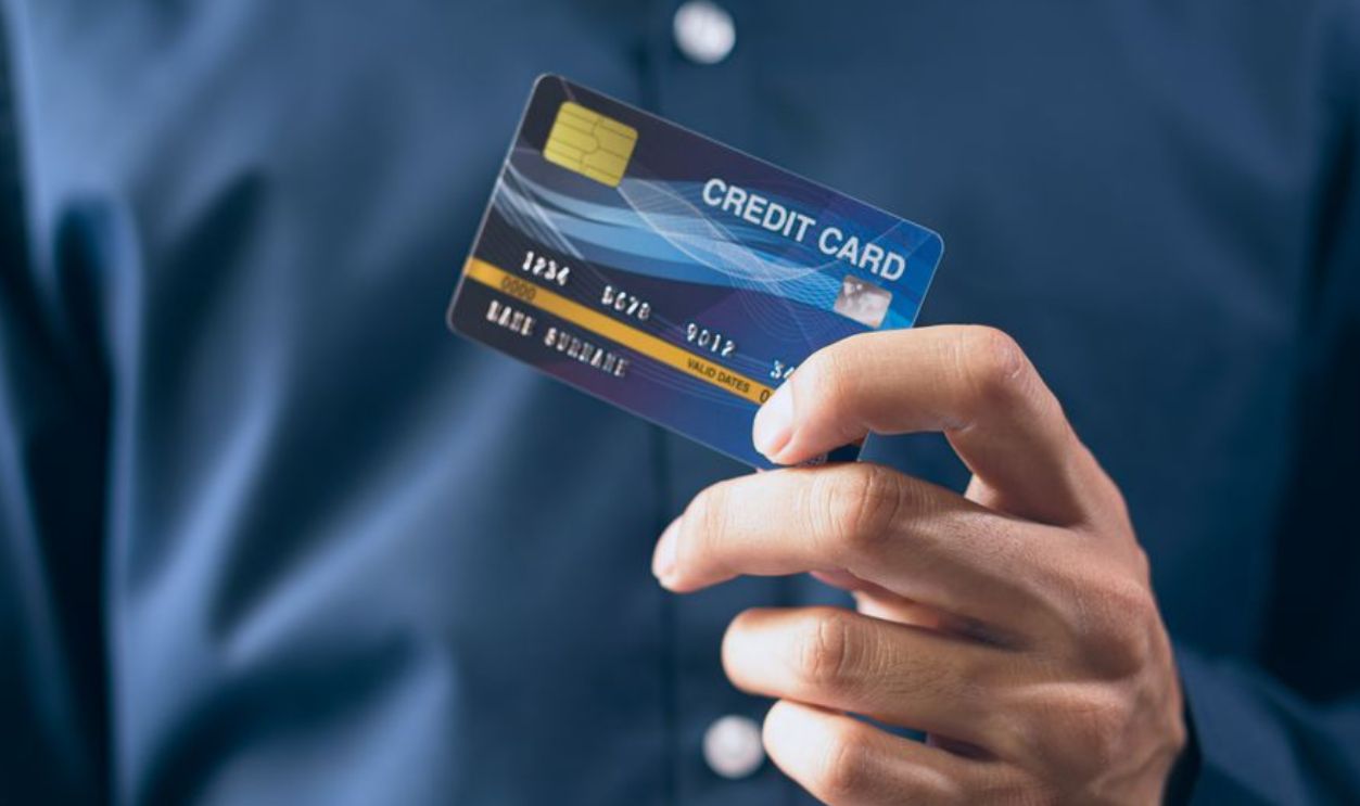 Close-up of a person holding a credit card in a hand, wearing a button-up shirt