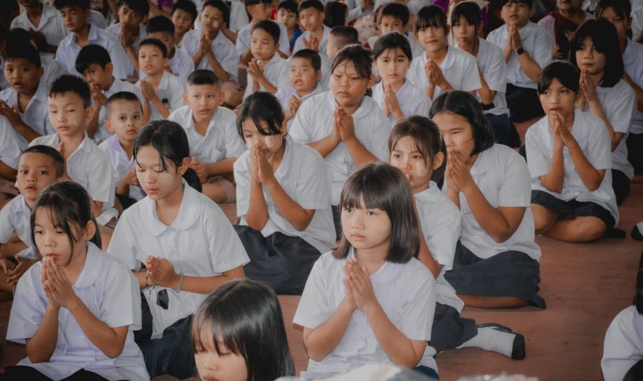 Students in uniform meditating at a school assembly, focused and serene.
