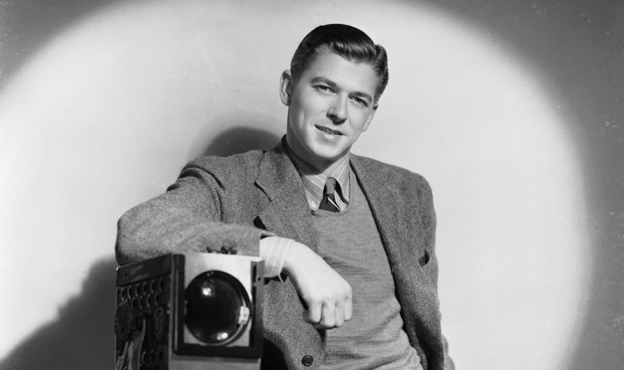 Promotional portrait of American actor and future US president Ronald Reagan (1911 - 2004) posing in a spotlight and leaning on a camera, circa 1939.