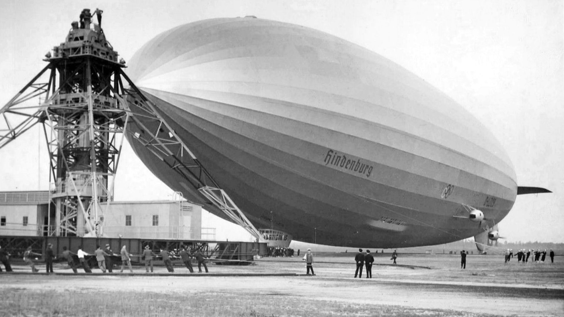 Photo of the Hindenburg being moored at Lakehurst, NJ after its first transatlantic crossing to the US.  The Olympic rings logo can be seen on the side of the airship.