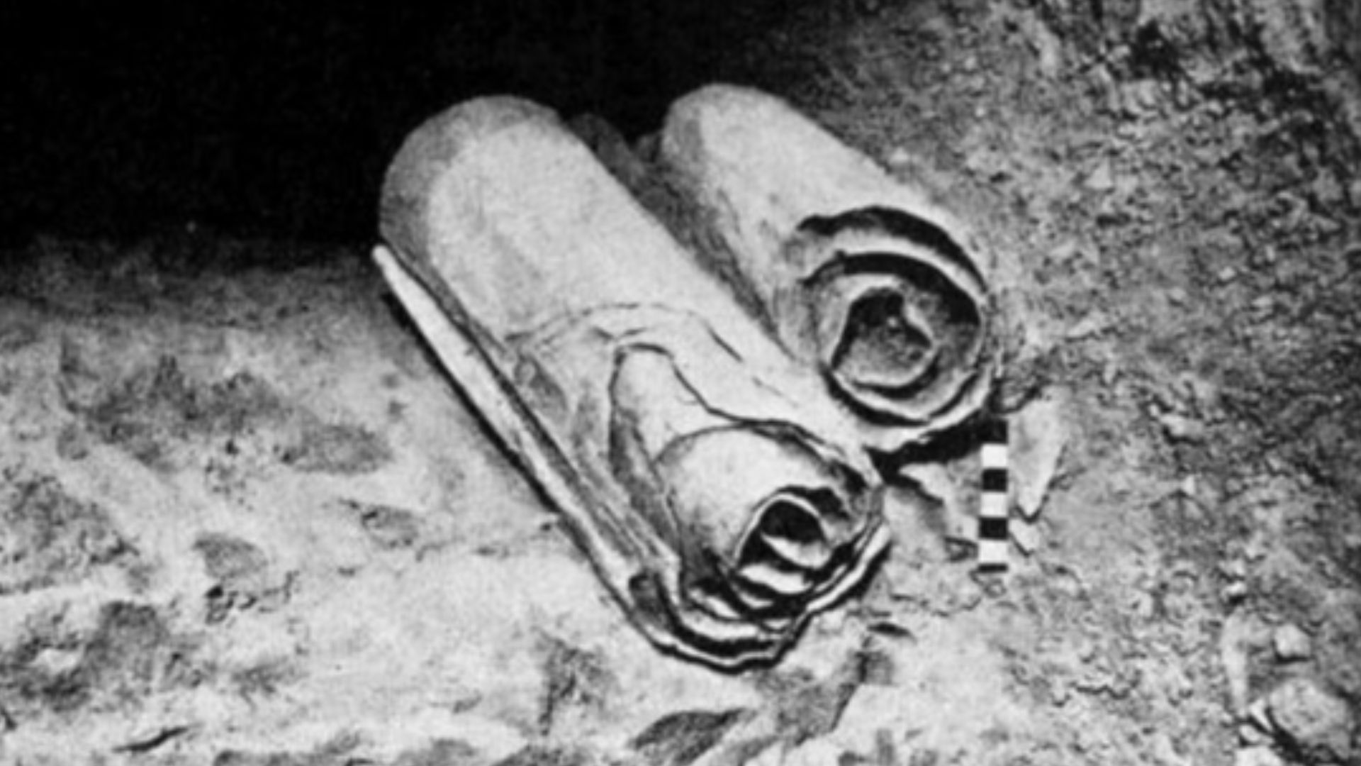 Two scrolls from the Dead Sea Scrolls lie at their location in the Qumran Caves before being removed for scholarly examination by archaeologists.